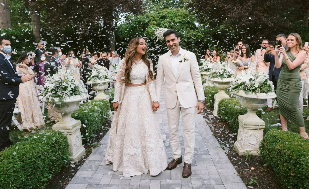 Image of happy couple while wedding guest surround them with confetti in the air.