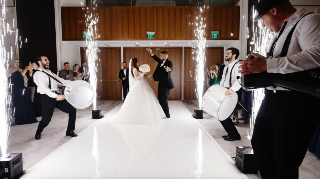 Image of bride and groom in wedding venue while performers with drums surround them.